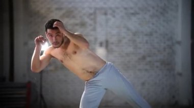 Atletik adam capoeira egzersizleri yapıyor - etrafında dönüyor ve tuğla duvarlarile bir odada bacak kaldırma