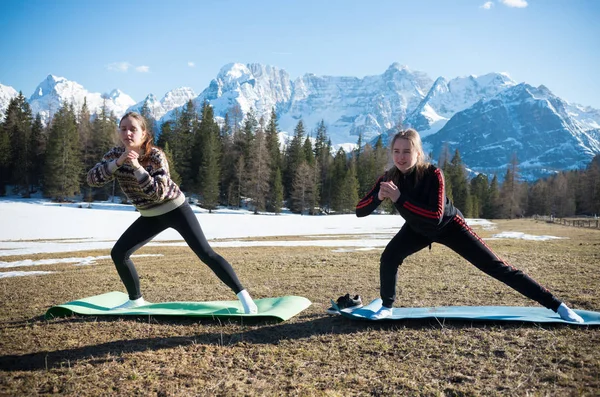 Dolomity-dwie młode kobiety robią fitness na tle lasu — Zdjęcie stockowe