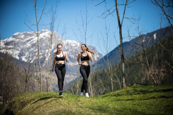 Dolomity-dvě mladé atletické ženy běžící na hřišti — Stock fotografie