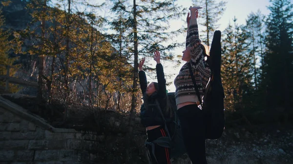 Dvě mladé ženy, které stojí a vytahují ruce vzhůru do hor Dolomitů — Stock fotografie