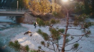 Dağlarda bir köprü altında sırt çantaları ve gitar ile kayalık nehir yakınında atlama iki genç kadın