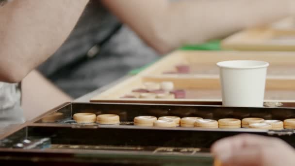 Ein Mann sitzt am Tisch und spielt Backgammon im Freien — Stockvideo