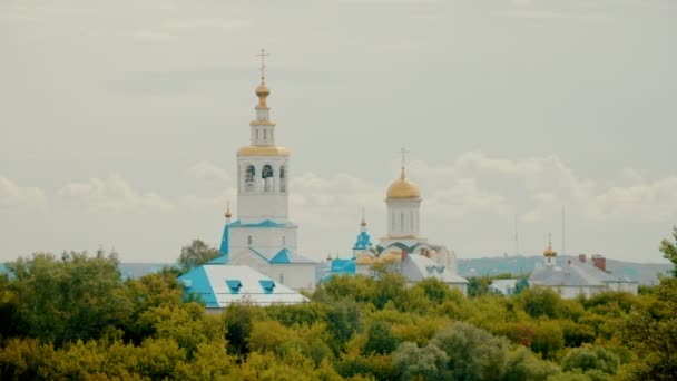 Vista de la ciudad de la iglesia blanca y el bosque verde brillante - El cielo está cubierto de nubes — Vídeo de stock