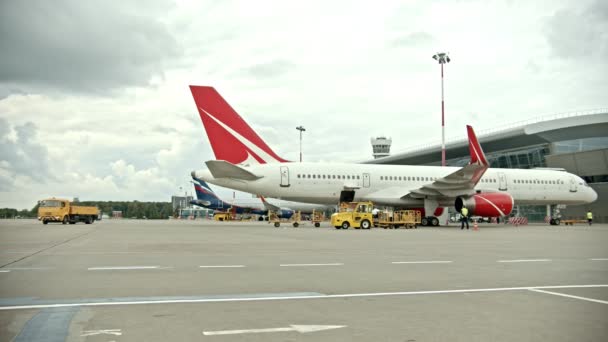 Duży samolot stojący na lotnisku w terenie-załadunek bagażu wewnątrz samolotu — Wideo stockowe