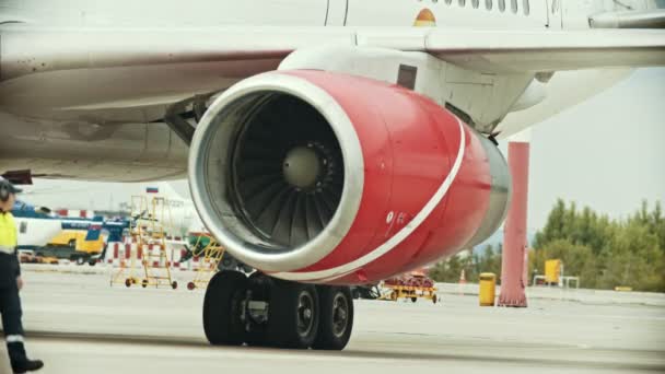Een vliegtuig op de luchthaven veld-warme lucht afkomstig van de turbine-een man werknemer langskomen — Stockvideo