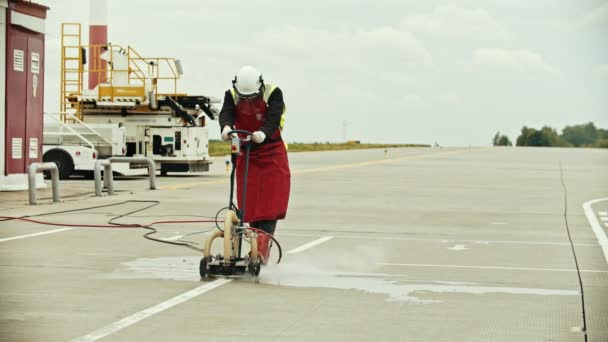 Seorang pekerja wanita tua membersihkan lapangan udara aspal — Stok Video