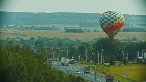 Colorful air balloon flying above the road — Stock Video