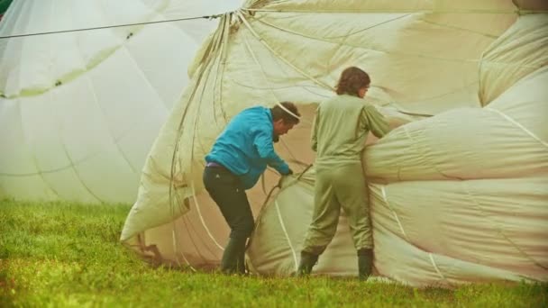 18-07-2019 Pereslavl-Zalessky, Rusia: dos hombres preparando globos aéreos para volar y alisar la tela — Vídeo de stock