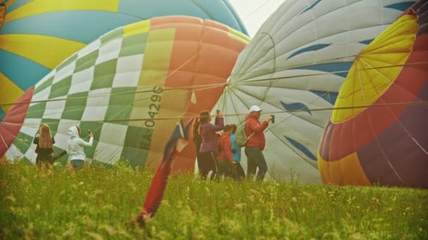 18-07-2019 Pereslavl-Zalesskij, Rusko: obrovské barevné vzduchové balónky ležící na poli-lidé chodí kolem a natáčíme ho na fotoaparáty — Stock video