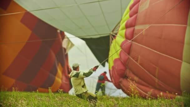 18-07-2019 Pereslavl-Zalessky, Rosja: mężczyzna trzymający ogromny balon powietrzny przez linę i trudny do ciągnięcia go na niego — Wideo stockowe