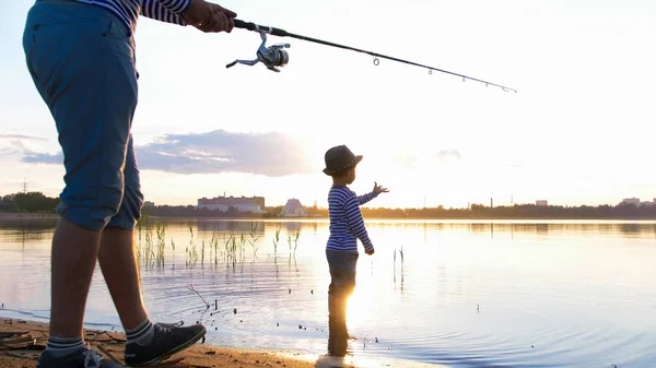 Батько і син рибалка на березі річки на заході сонця — стокове фото