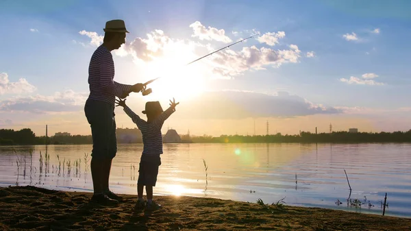 Vater und Sohn angeln am Ufer des Flusses im Sonnenuntergang — Stockfoto