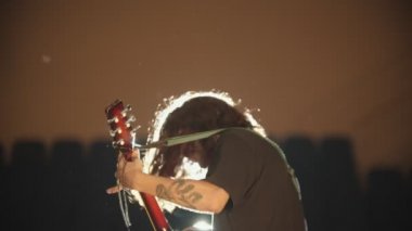 Uzun saçlı Genç bir adam onun performansında bir şarkı oynuyor ve kafasını sallayarak