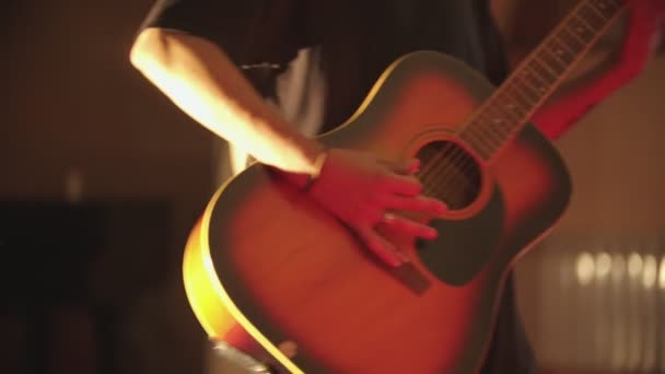 Un uomo che suona la chitarra acustica alla sua performance in luci brillanti — Video Stock