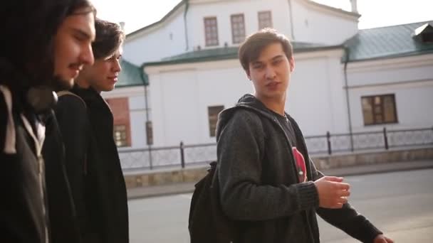 Mladí přátelé v tmavých šatech, kteří chodí po ulici — Stock video