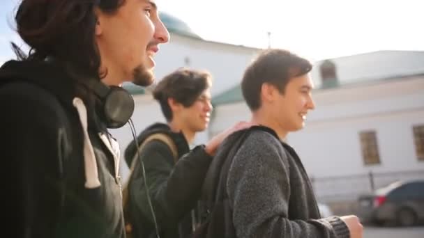 Jovens amigos felizes em roupas escuras andando na rua — Vídeo de Stock