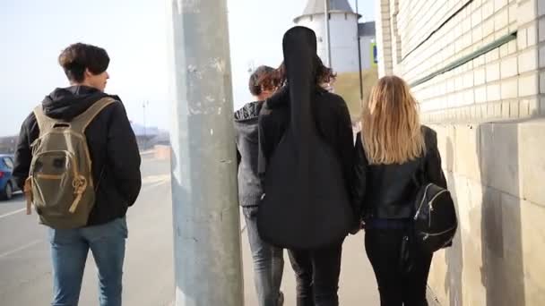Νέοι φίλοι με σκοτεινά ρούχα που περπατούν στο δρόμο την ημέρα — Αρχείο Βίντεο