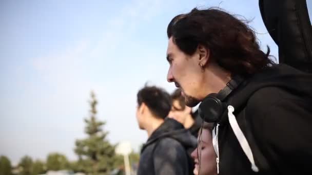 Jonge gelukkige vrienden in donkere kleren lopen op straat en praten — Stockvideo