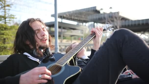 Ein junger Mann spielt Gitarre und singt — Stockvideo