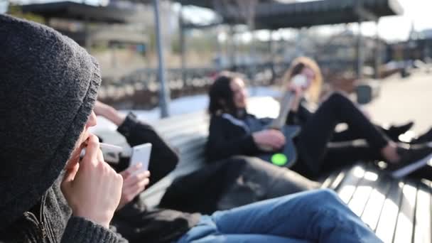 Jóvenes amigos que se relajan en un banco - dos hombres fumando — Vídeos de Stock