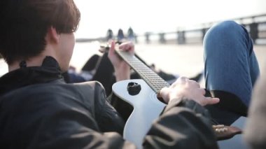 Bir bankta yatan ve gitar çalan genç bir adam