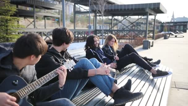 Junge Freunde chillen auf einer Bank - trinken Alkohol und spielen Gitarre — Stockvideo