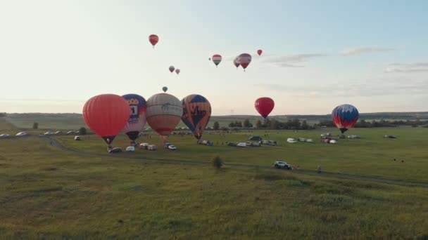 18-07-2019 Suzdal, Rusko: různé pestrobarevné vzduchové balónky se sunují přes polní automobily a náklaďáky stojící na hřišti-časný večer — Stock video