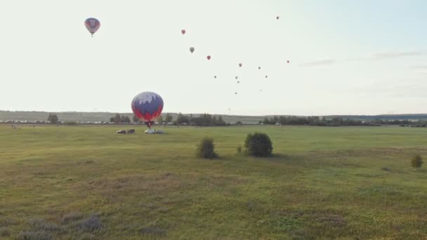 18-07-2019 suzdal, russland: verschiedene Luftballons fliegen über das Feld - der letzte Ballon ist startklar - früher Abend — Stockvideo