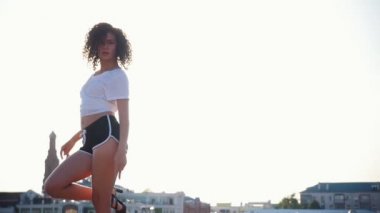 Parlak güneş ışığı-modern binaların bir arka planda çekiciyle dans kıvırcık saçlı bir melez genç kadın