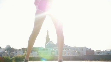 Modern binaların bir arka planda kıvırcık saçlı seksi dans ile çekici melez genç kadın-parlak güneş ışığı