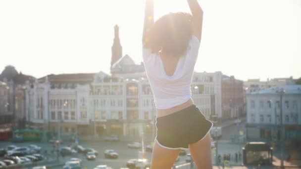 近代的な建物の背景に踊る巻き毛を持つ魅力的なムラット若い女性 - 夕日 — ストック動画