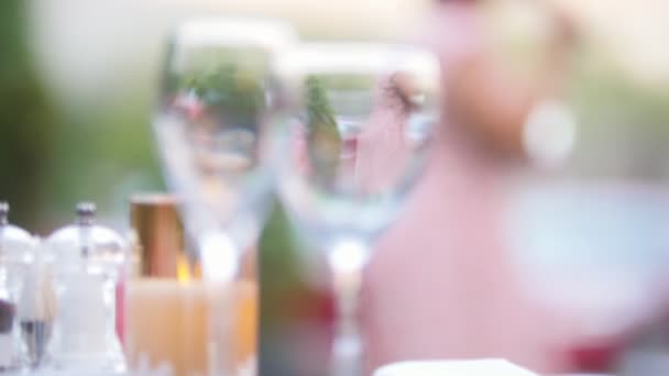 Gafas de pie sobre la mesa - una mujer reflejada en el vaso — Vídeos de Stock