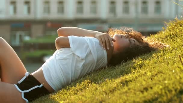 Attraktive magere junge Frau, die auf dem Gras liegt und sich mit den Händen umarmt - dann aufsteht — Stockvideo