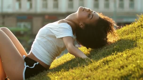 Vonzó sovány fiatal nő göndör hajú Állj fel a füvön, és keresi a kamera — Stock videók