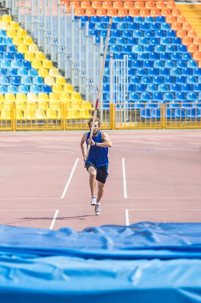 Pole vault - бородатый человек бежит вверх держа столб перед прыжком . — стоковое фото