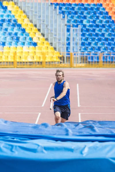 Stavhopp-en skäggiga atletisk man springer upp håller en stolpe innan hoppning. — Stockfoto