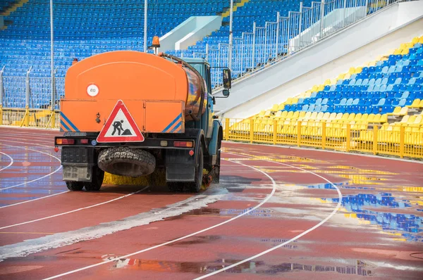 A big cleaning machine washes the running track with water stream in the stadium — Stock Photo, Image