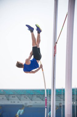 Pole vault - genç bir atletik adam kutup üzerinde yere karşı dinlenme ve atlamak için hazır