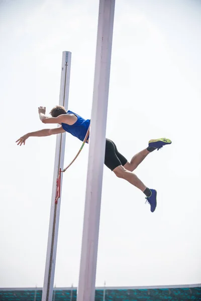 Stabhochsprung - ein junger, athletischer Mann springt über die Latte — Stockfoto