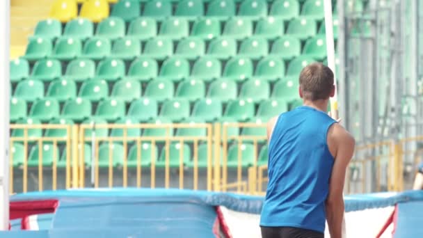 Bóveda de poste: un joven se prepara y comienza a correr sosteniendo un poste en el estadio — Vídeo de stock