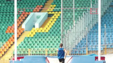 Sırıkla atlama - mavi gömlekli genç bir adam barın üzerinden atlar