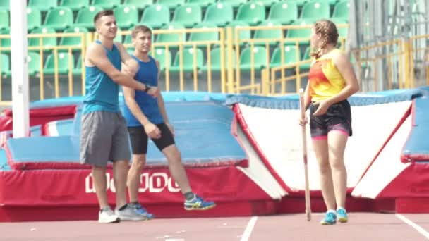 Kazan, Rusya 26-07-2019: stadyumda sırıkla atlama antrenmanında üç atletik insan konuşuyor ve gülüyor. Orta atış — Stok video