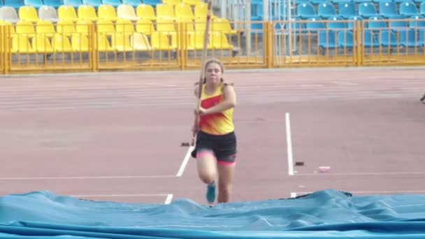 KAZAN, RUSIA 26-07-2019: una joven saltando por encima de la barra con un esfuerzo: entrenamiento de bóveda de pértiga en el estadio — Vídeo de stock