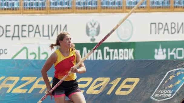 KAZAN, RUSIA 26-07-2019: una joven con coletas saltando sobre la barra con un esfuerzo - entrenamiento de bóveda de pértiga en el estadio — Vídeo de stock