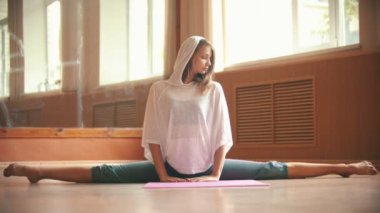 Genç güzel kadın yoga mat üzerinde oturan bir bölünmüş performans - bacak germe egzersizleri yapıyor - dans stüdyosu