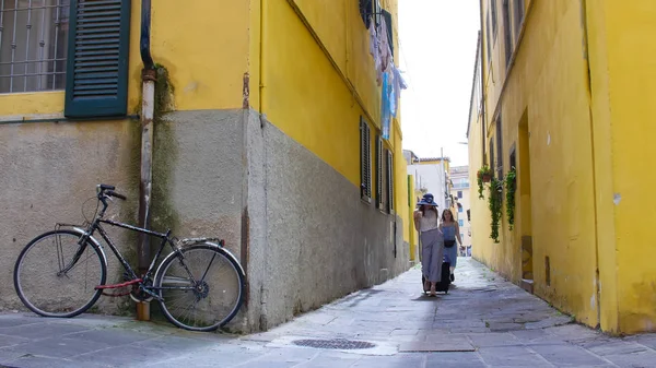 stock image Two young excited women walking through the narrow yellow streets with luggage