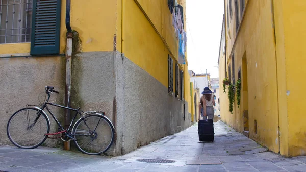 Две молодые женщины идут по узким желтым улицам с багажом — стоковое фото