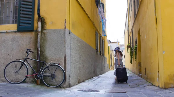 Una joven caminando por las estrechas calles amarillas con equipaje —  Fotos de Stock