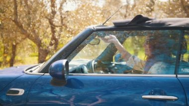 Cabriolet oturan ve çatı açılması genç bir kadın - Güneşli gün