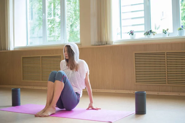 Junge schlanke Frau sitzt im Tanzstudio auf der Yogamatte — Stockfoto